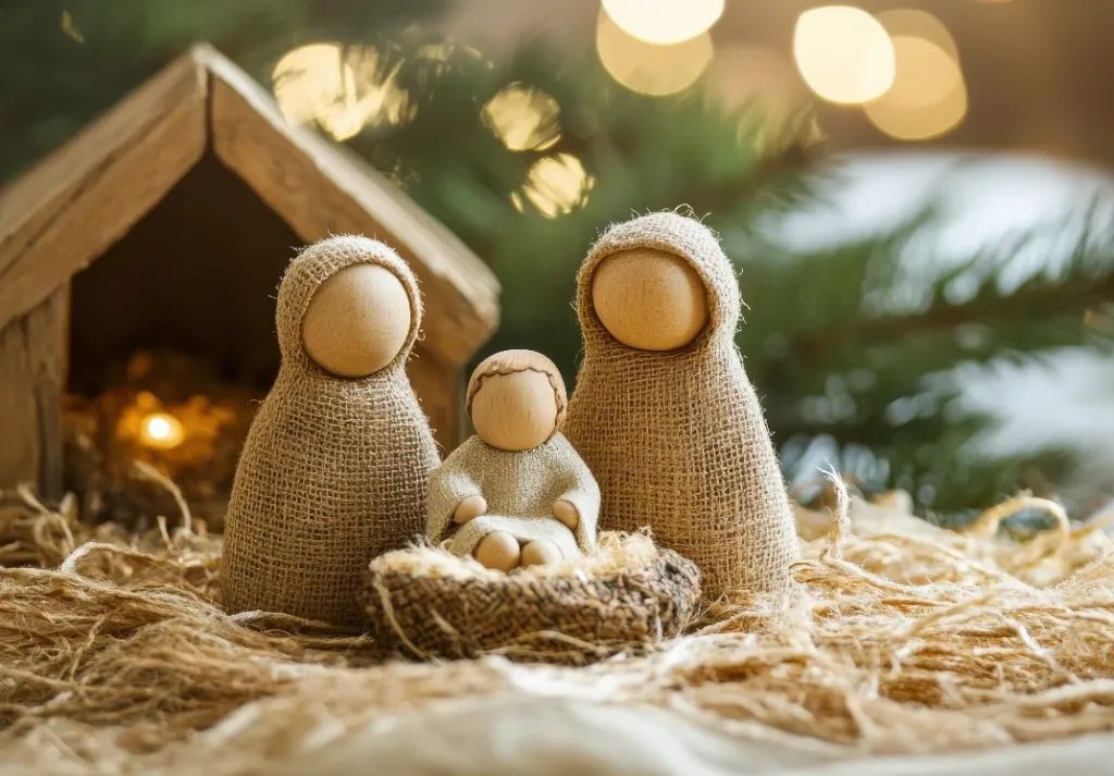 Rustikale Krippe aus Holz mit Maria, Josef und Jesuskind vor Lichtern und Tannenzweigen