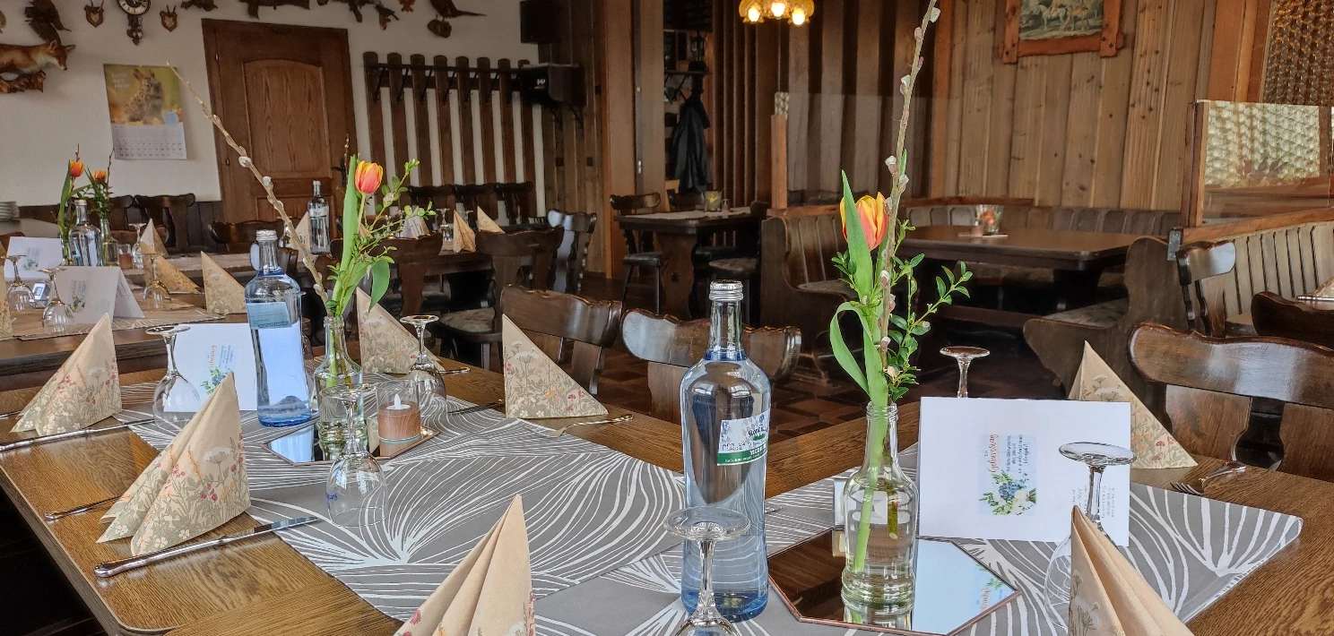 Jägerzimmer mit für eine Veranstaltung eingedeckter Tafel mit Blumenvasen und Servietten