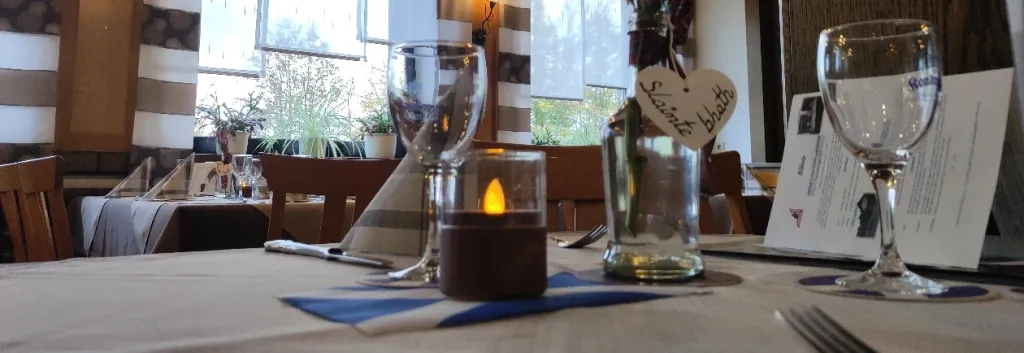 Festlich gedeckter Tisch mit Weingläsern, Kerze und Holzherz im großen Gastzimmer