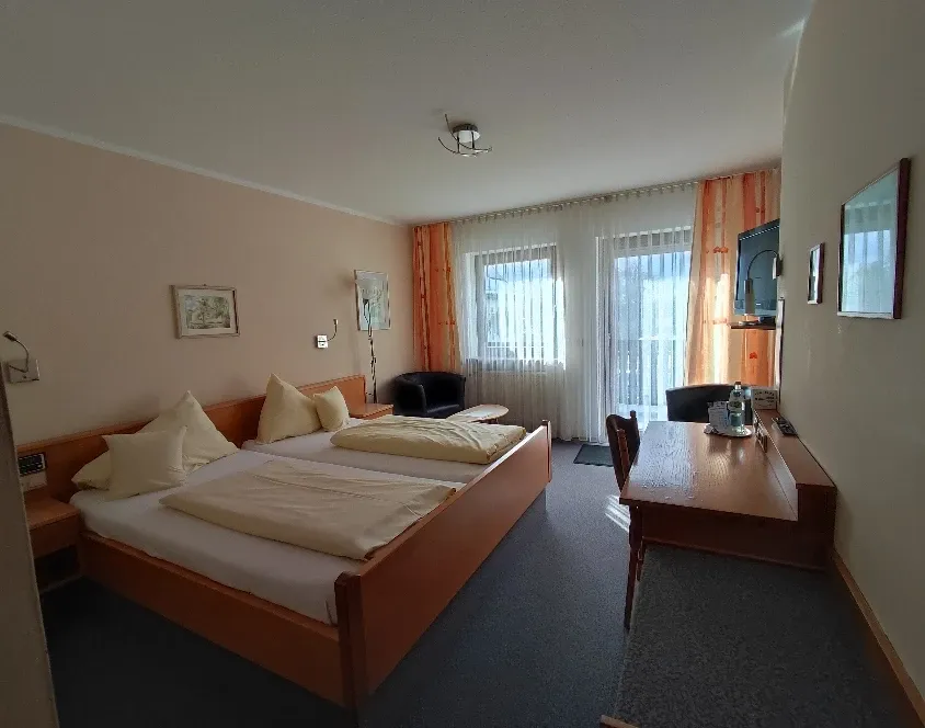 Helles Doppelzimmer mit zwei Einzelbetten, Schreibtisch und Fenster zum Balkon