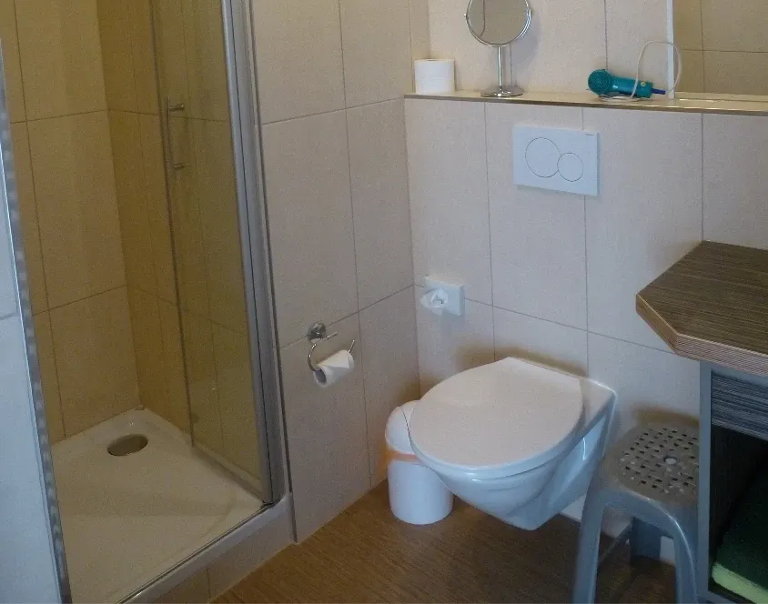 Helles Apartment-Badezimmer mit Eckdusche, Wand-WC und beigefarbenen Fliesen