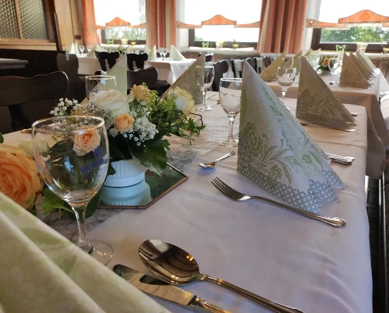 Tischdetail im Jägerzimmer mit Rosenstrauß, Weingläsern und gefalteten Servietten