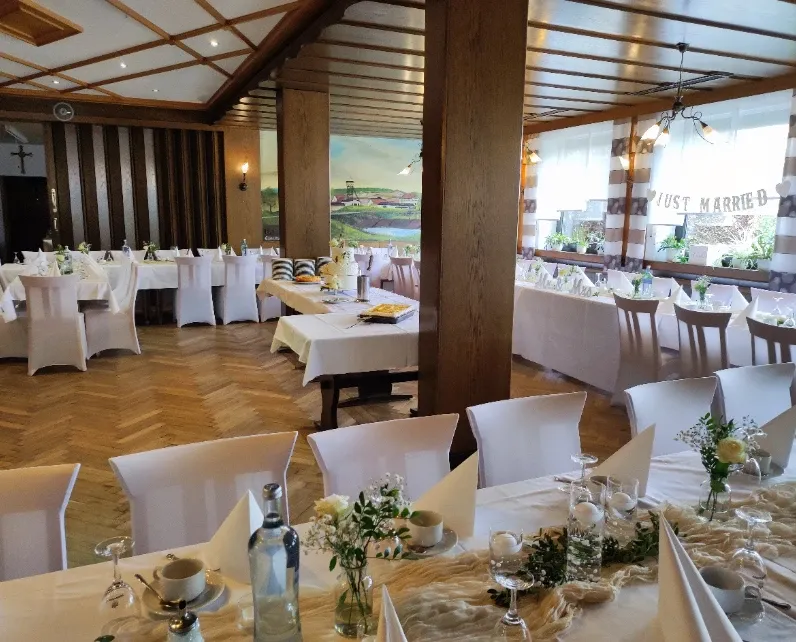 Hochzeitstafel mit Hochzeitstorte, weißen Stuhlhussen und Wandgemälde im großen Gastzimmer