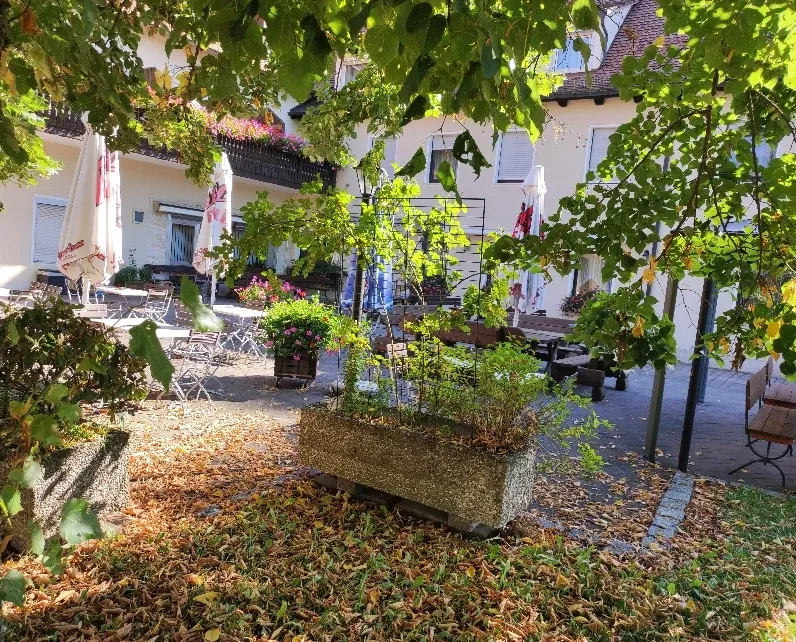 Herbstlicher Innenhof mit Pflanztrog und buntem Laub vor dem Gasthof