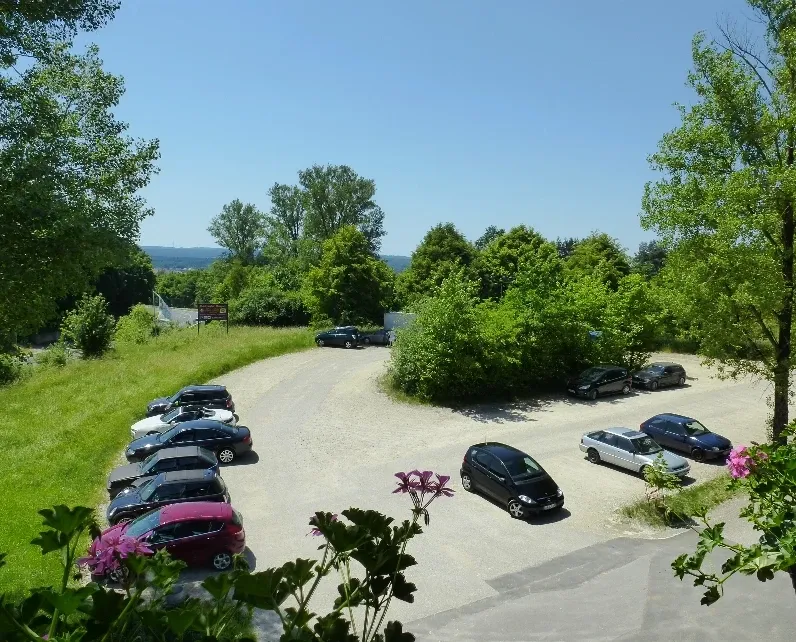 Hauseigener Parkplatz mit parkenden Autos, gesäumt von Bäumen