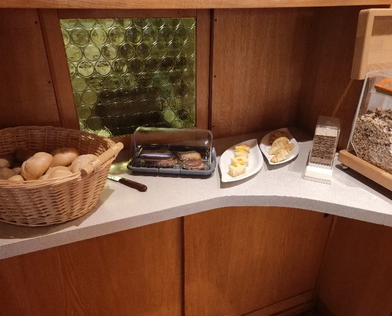Frühstücksbuffet mit Brotkorb, Marmeladen und Butter in einer Holznische
