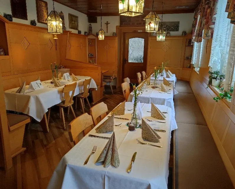 Kleines Gastzimmer mit Holzvertäfelung, bunten Laternen und eingedeckten Tischen