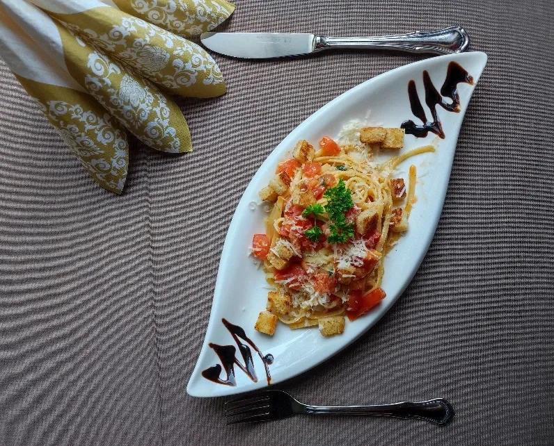 Linguine mit Tomaten und Parmesan auf länglichem Teller mit Brot