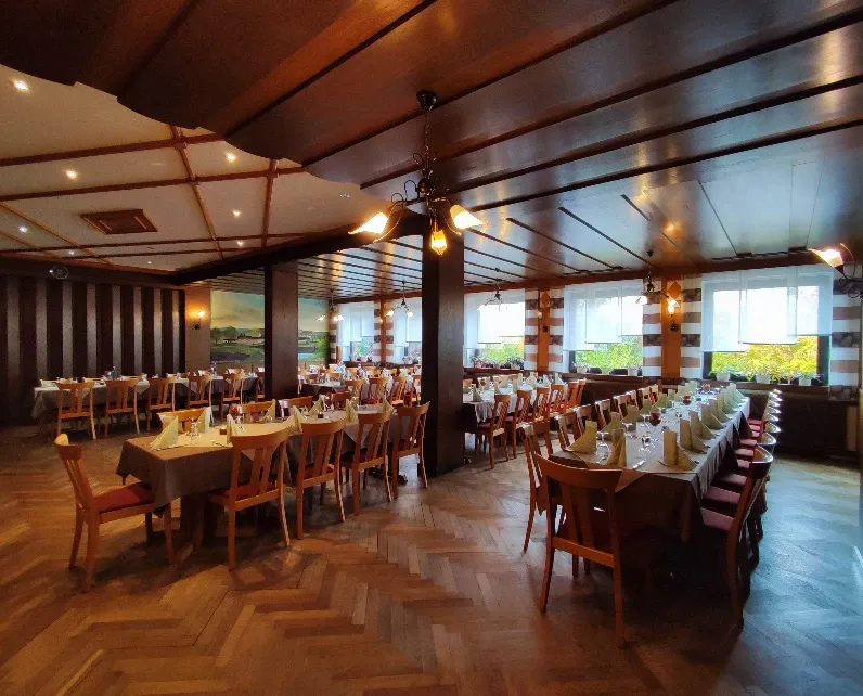 Großes Gastzimmer mit Holzdecke, Hängelampen und für eine Feier eingedeckten Tischen