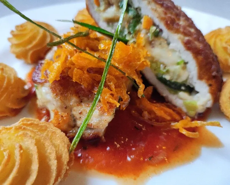 Gefülltes Schnitzel mit Karottenstreuseln, Schnittlauch und Herzoginkartoffeln auf Tomatensoße