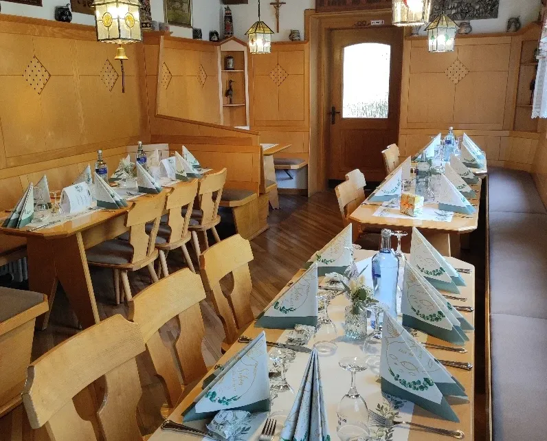 Kleines Gastzimmer mit für eine Veranstaltung eingedeckten Tischreihen unter Hängelampen