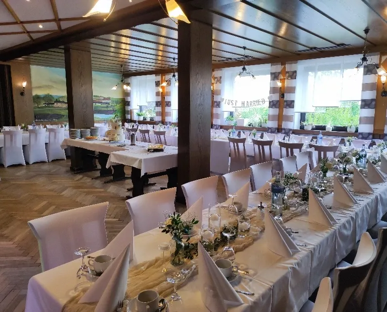 Hochzeitstafel im großen Gastzimmer mit weißen Stuhlhussen und „Just Married“-Banner