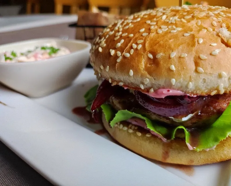 Hausgemachter Burger mit Sesambrötchen, Rote-Bete-Soße, Salat und Krautsalat-Dip