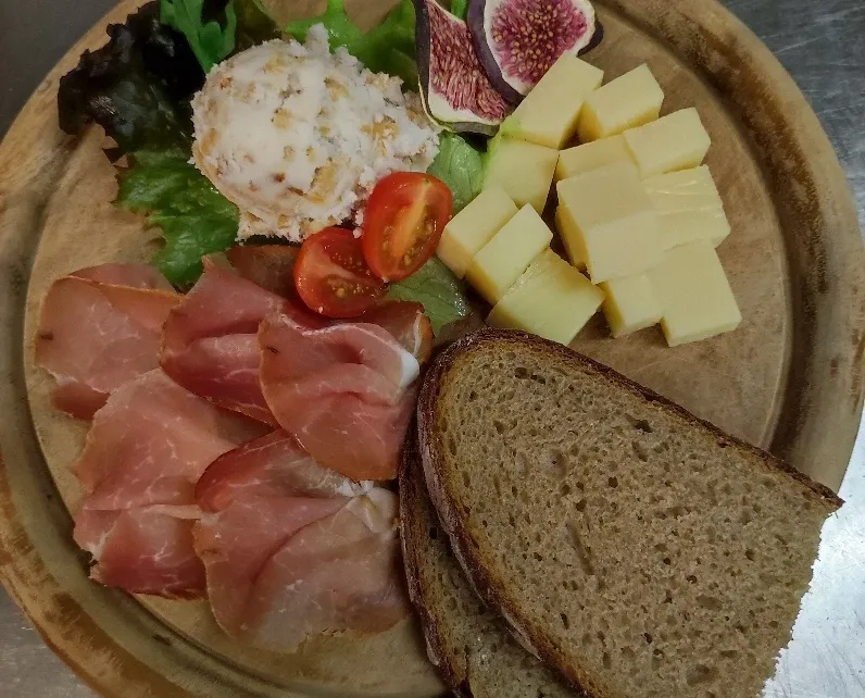 Brotzeitbrett mit Schinken, Käsewürfeln, Feigen, Frischkäse, Brot und Salat