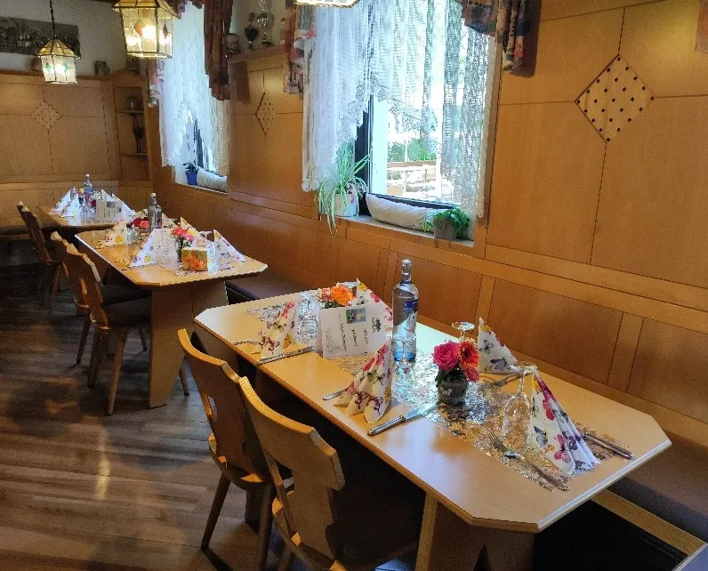 Kleines Gastzimmer mit eingedeckter Tafel vor Fenster mit Spitzengardinen
