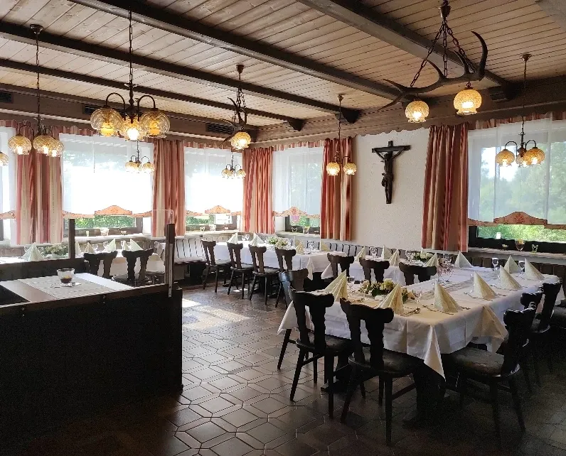 Jägerzimmer mit für eine Feier eingedeckter Hufeisentafel und Kruzifix an der Wand