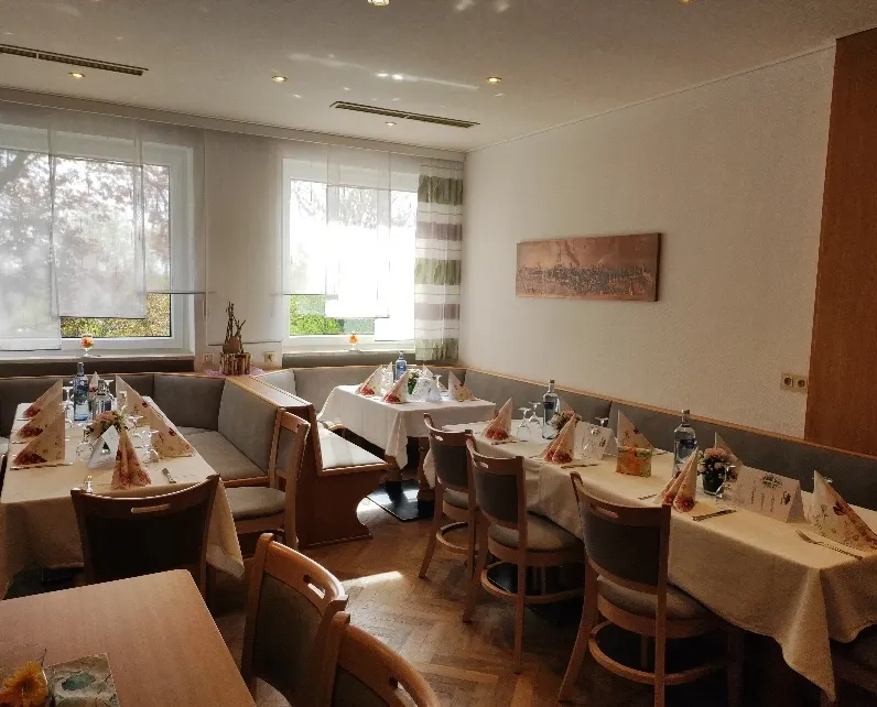 Frühstückszimmer mit für eine Veranstaltung eingedeckten Tischreihen vor Fenstern